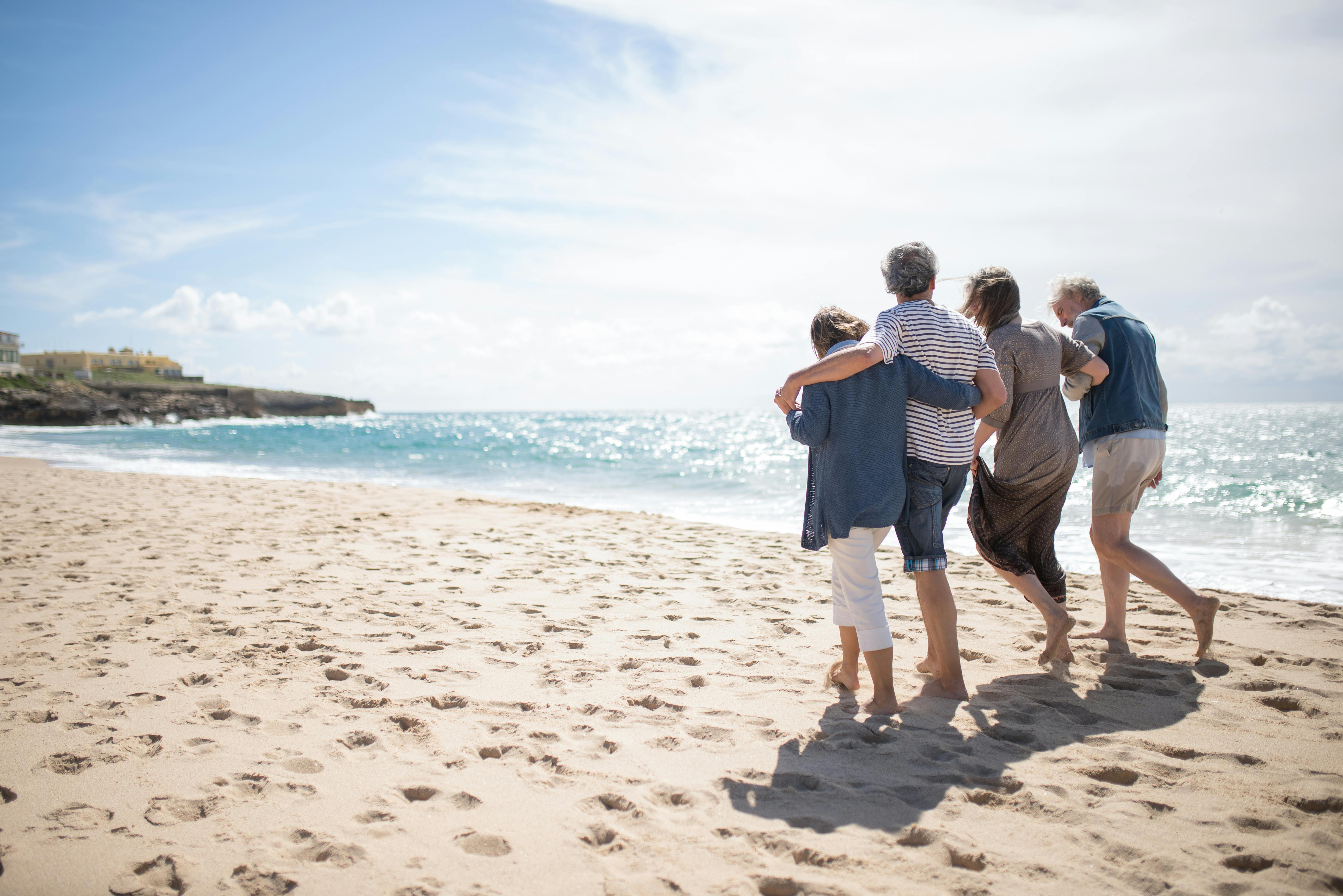 two adult couples walking along the beach